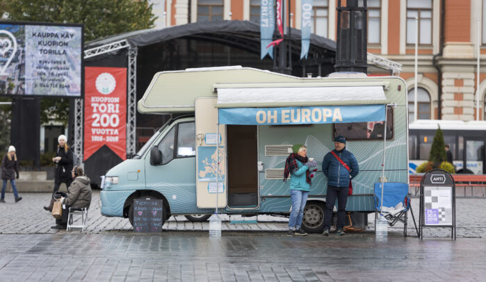 A camper van at the Kuopio Market Square. Some people around the van.